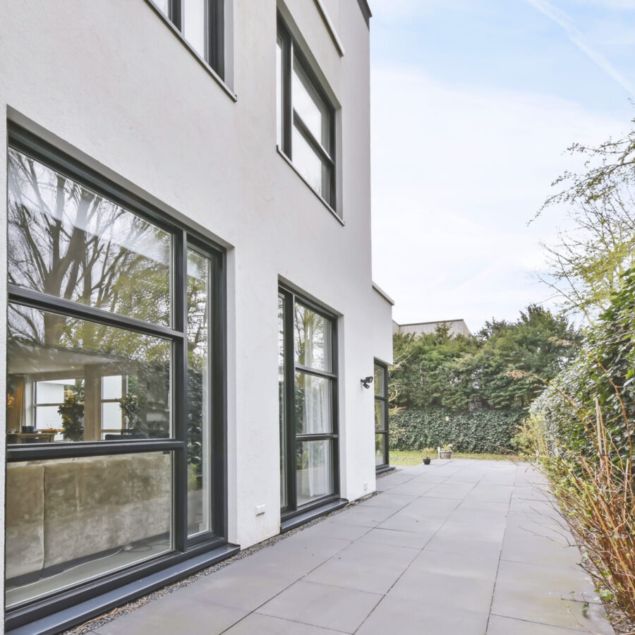 The courtyard of the house is in a minimalist style with large windows with a black frame